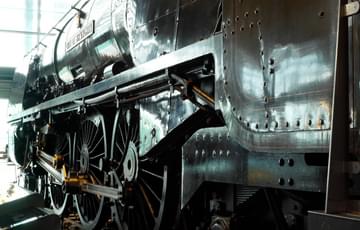 Side view of front wheels and engine of a steam locomotive train