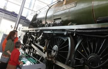 A family looking up at a steam train on display.