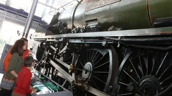 A family looking up at a steam train on display.