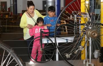 An adult and two children looking at bicycles on display.
