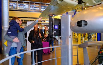 A family observes and points at part of the Railton Land Speed car on display.