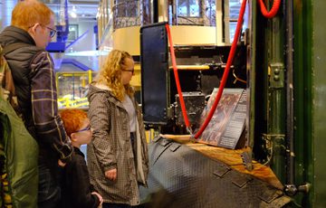Two adults and child observe an historic train exhibit in a museum.