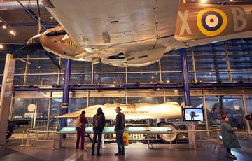 Visitors observe the Railton land speed car displayed inside a museum gallery.