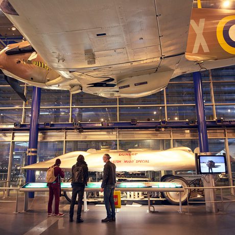 Visitors observe the Railton land speed car displayed inside a museum gallery.