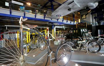 A Penny Farthing bicycle with its high front wheel and small back wheel. The seat is high up above the front wheel.