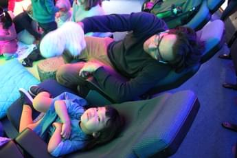 A child and adult sitting in the Planetarium. The child is looking up at the ceiling.