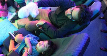 A child and adult sitting in the Planetarium. The child is looking up at the ceiling.