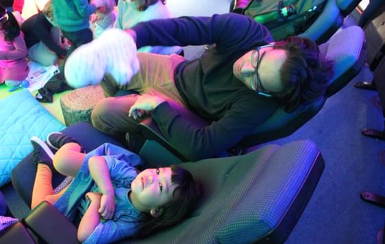 A child and adult sitting in the Planetarium. The child is looking up at the ceiling.