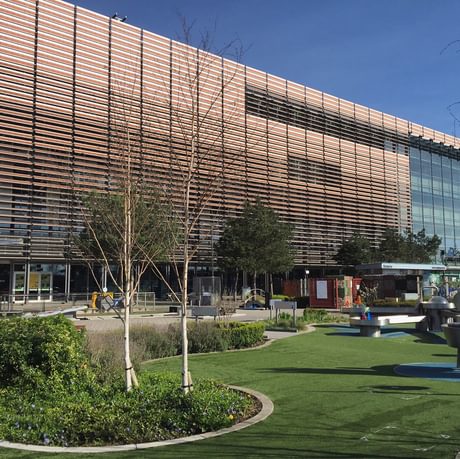 A large modern building with garden in front. In the garden is trees, plants and science exhibits