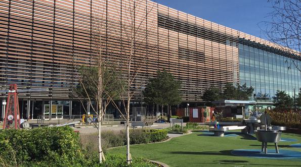 A large modern building with garden in front. In the garden is trees, plants and science exhibits