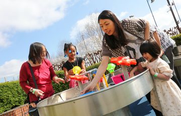 A family with two adults and 2 children playing in a water feature in the Science Garden.
