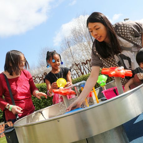 A family with two adults and 2 children playing in a water feature in the Science Garden.