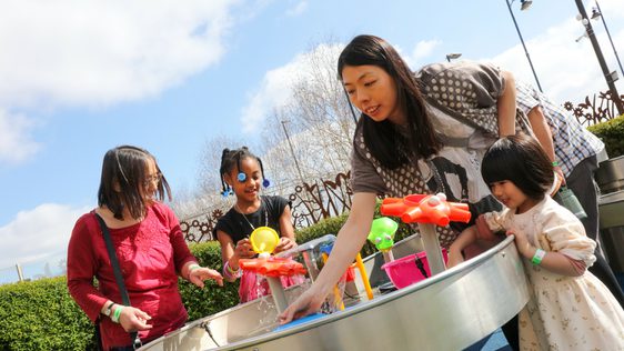 A family with two adults and 2 children playing in a water feature in the Science Garden.