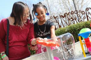 An adult and child playing with an interactive water feature.