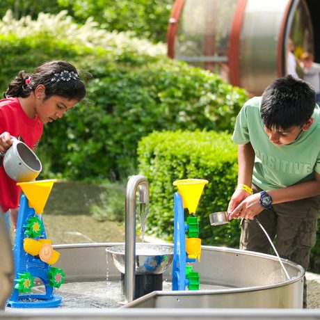 Two children play with colourful water toys in the outdoor Science Garden.