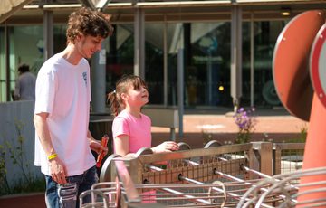 A young man and girl play an outdoor exhibit, they are smiling and enjoying the moment together.