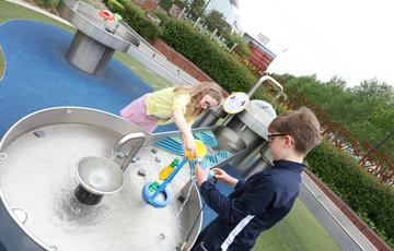 Two children playing with an interactive water exhibit