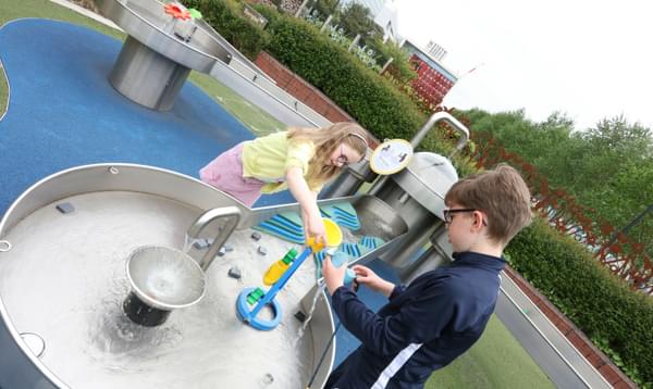 Two children playing with an interactive water exhibit