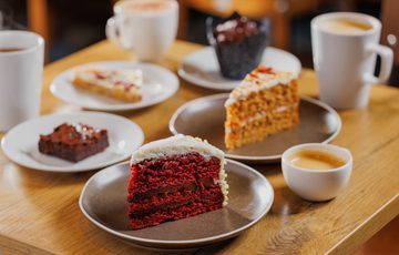 A selection of cakes, desserts and hot drinks on a table.