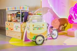 Brightly-coloured coffee kiosk behind a mobile ice cream fridge attached to a bicycle