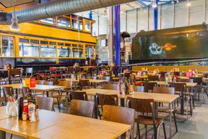 Café dining area in large exhibition hall, an old tram and steam locomotive train are in the background