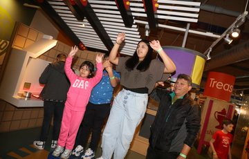 A family waving their hands in the air interacting with an exhibit.