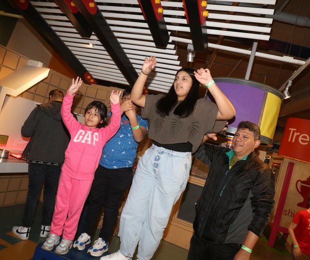 A family waving their hands in the air interacting with an exhibit.