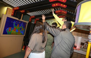A family waving their hands in front of a TV screen which is showing them as a thermal image.