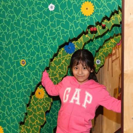 A child walking underneath plastic bushes.