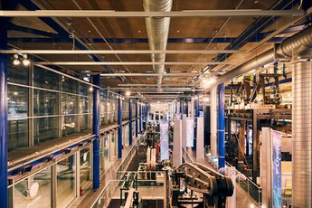 Industrial museum interior with machinery, metal beams, and overhead ventilation ducts.