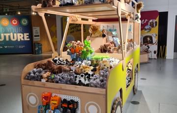 A wooden jeep that is full of cuddly animal toys for sale.