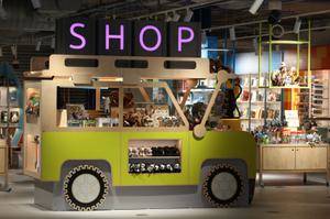 A shop display in the shape of a yellow jeep. It is displaying cuddly toy animals, books and games.
