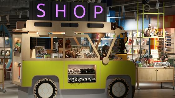 A shop display in the shape of a yellow jeep. It is displaying cuddly toy animals, books and games.