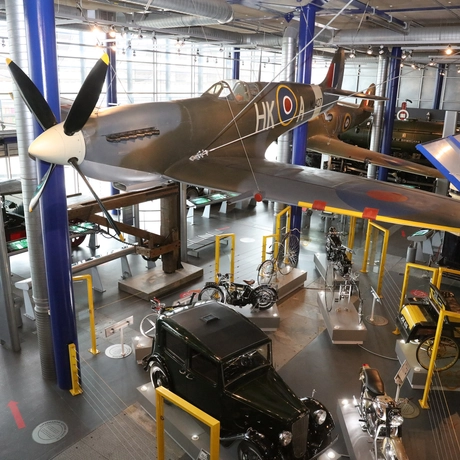 A gallery with planes on display with vehicles below.