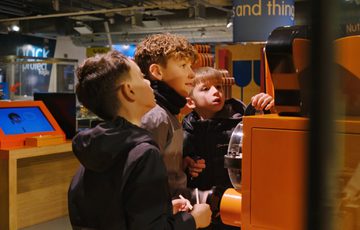 Three boys intently explore an interactive exhibit in the gallery.