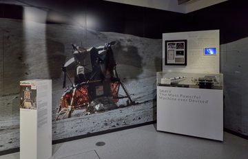 Two display cases with a large photograph of a module on the moon.