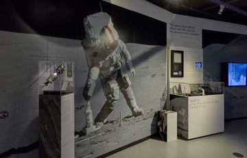 Two display cases with a large photograph of man on the moon.