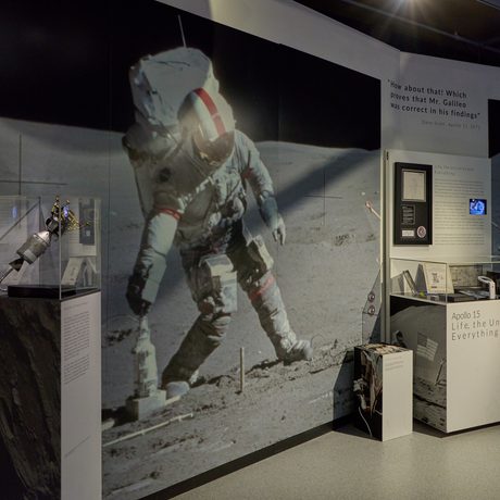 Two display cases with a large photograph of man on the moon.