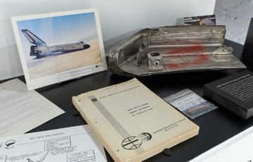 Display case of objects including photos, manuals, and part of a Insulation Panel.