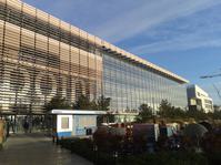 Exterior of Millennium Point building from Parkside. It is a modern glass building with trees in font and there is a blue sky in the background.