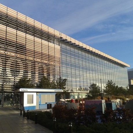 Exterior of Millennium Point building from Parkside. It is a modern glass building with trees in font and there is a blue sky in the background.