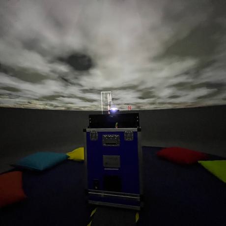 Inside the planetarium with a cloudy sky projected onto the ceiling.