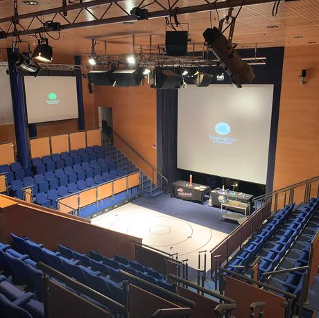 An empty theatre space with seating on three sides.