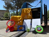 Family backpacks with contents laid out on the floor in the science garden.