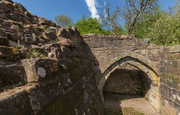 Close view of two ruined castle walls joined by a pointed stone arch