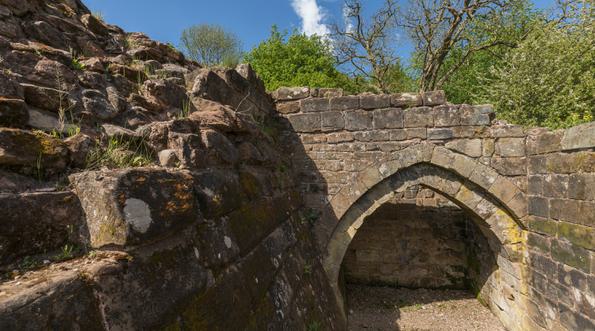 Close view of two ruined castle walls joined by a pointed stone arch