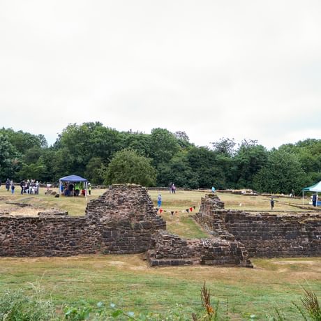 Weoley Castle ruins from a distance with people and gazebos on the grass inside the ruins.