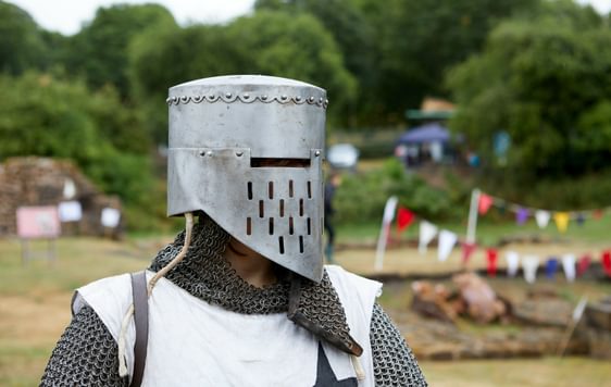 Head and shoulders of a re-enactor dressed as a medieval knight who is looking to the side.