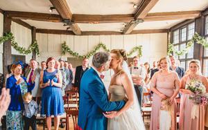 A bride and groom kissing in front of their guests in a Tudor house.