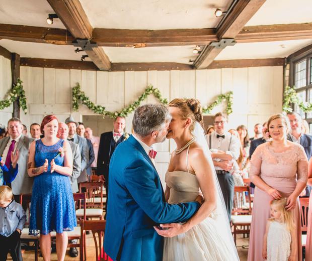 A bride and groom kissing in front of their guests in a Tudor house.